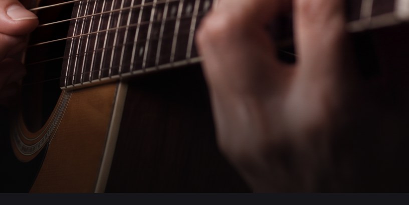 Close-up of hands playing chords on an acoustic guitar